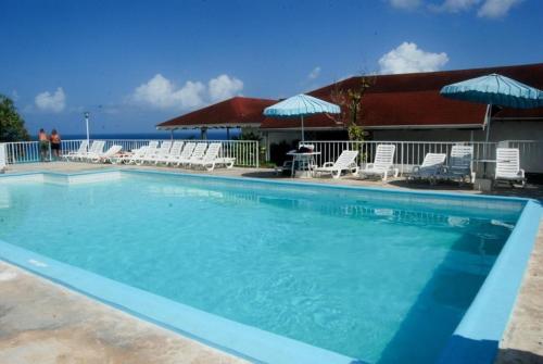 una gran piscina con sillas y sombrillas en Ocean View Montego Bay Apartment en Montego Bay