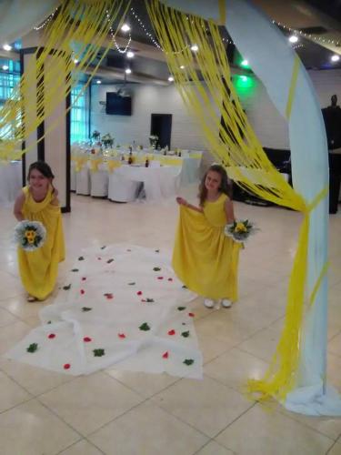 two young girls in yellow dresses standing in a room with a table at Everest Hotel in Etropole