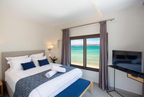 a bedroom with a bed and a window with the ocean at Tiamo Secrets - Beach Front in Vourvourou