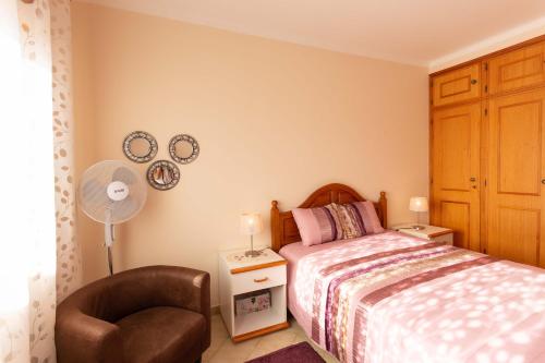 een slaapkamer met een bed, een stoel en een ventilator bij Casa Sossego in Lagos