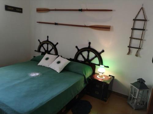 a bedroom with a green bed with two woodenwheels on the wall at B&B Villa Ines in Leuca