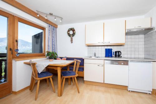a kitchen with white cabinets and a wooden table and chairs at Haus Konrad in Reith im Alpbachtal