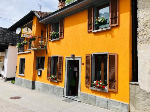 ein gelbes Gebäude mit Fenstern und einer Tür in der Unterkunft Donjon B&B e Ristorante in Someo