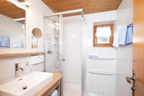 a white bathroom with a shower and a sink at Haus Konrad in Reith im Alpbachtal