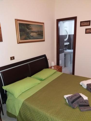 a bedroom with a green bed and a bathroom at B&B Villa Pegaso in Fontane Bianche