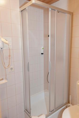 a shower with a glass door in a bathroom at Pension Leuprecht in Reutte
