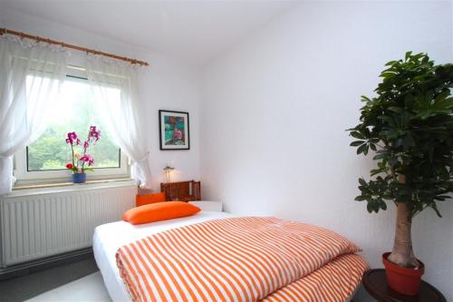 ein Schlafzimmer mit einem Bett mit orangefarbenem Kissen und einem Fenster in der Unterkunft Private Apartment in Hannover
