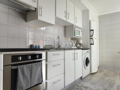 eine Küche mit weißen Schränken, einer Waschmaschine und einem Trockner in der Unterkunft House Seven in Horta