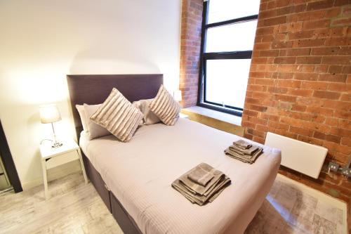 um quarto com uma cama com uma parede de tijolos em Aire Apartments New York Styled Luxury Apartments em Leeds