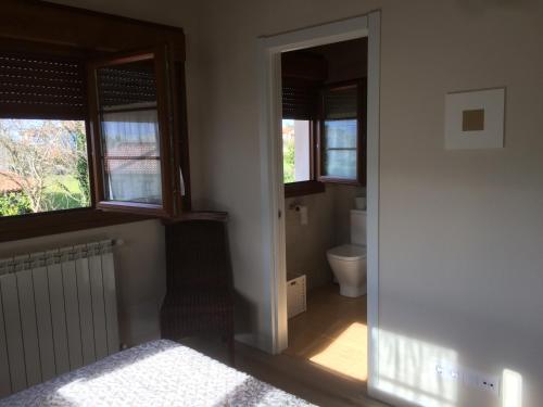 a bedroom with a bed and a toilet and windows at La Llastra de Garaña in Llanes