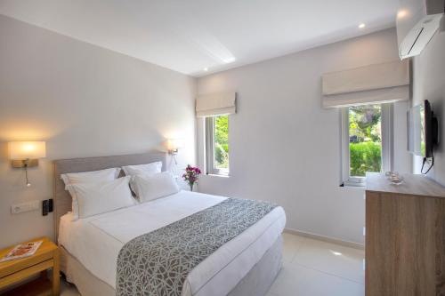 una camera bianca con un letto e due finestre di Tiamo Secrets - River Beach a Vourvourou