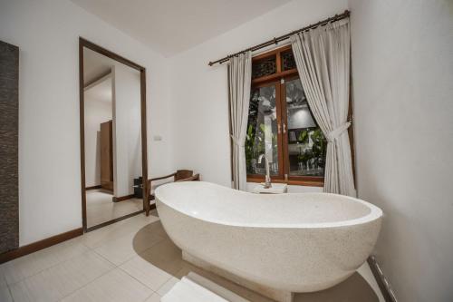 baño con bañera blanca y ventana en Villa Cinta Ubud, en Ubud