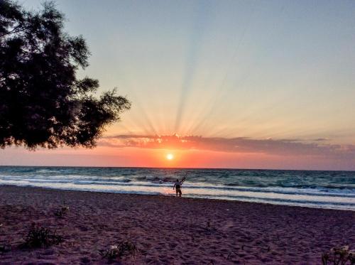 a person is standing on the beach at sunset at Villa Acacia in Phanaes