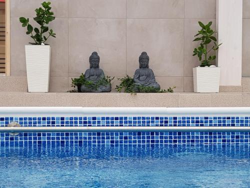 two statues sitting next to a swimming pool at Willa Rawia 2 in Rewal