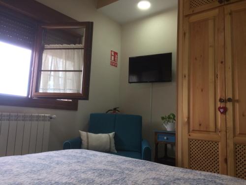 a bedroom with a bed and a blue chair and a television at La Llastra de Garaña in Llanes
