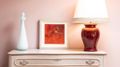 a table with a lamp and a picture and a vase at Villa Belverde Boutique Hotel in Carrara