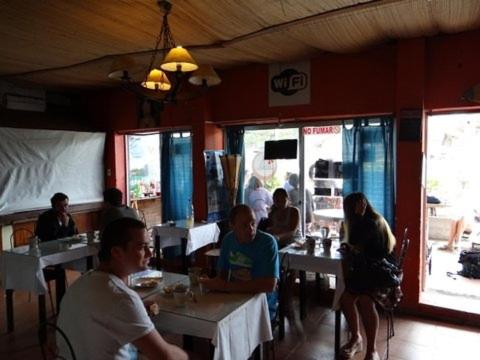 grupa ludzi siedzących przy stolikach w restauracji w obiekcie Hostel Ibirapita w mieście La Paloma