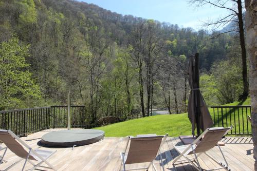 a deck with chairs and a table and an umbrella at Monyoya ,site exceptionnel au coeur des Pyrénées in Sarrance