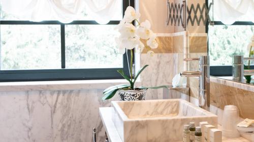 Villa Belverde Boutique Hotel في كارارا: حمام مع حوض مع إناء من الزهور