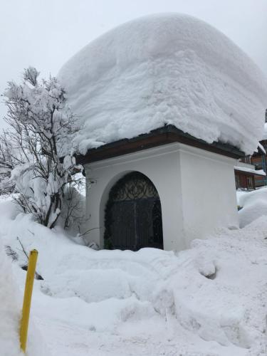 a snow covered building with a door and a pile of snow at Zur lieben Sonne in Filzmoos