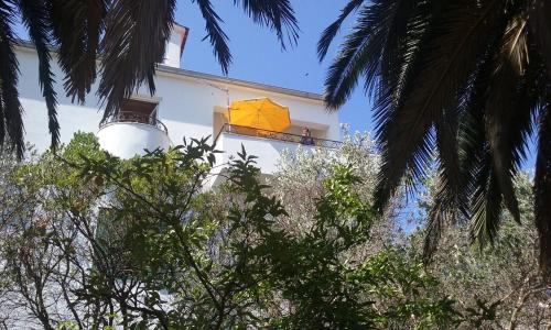 a yellow umbrella on a balcony of a building with trees at Villa Carmen in Sali