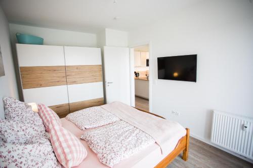 a bedroom with a bed and a tv on a wall at Strandchalet Elmo I in Wremen in Wremen