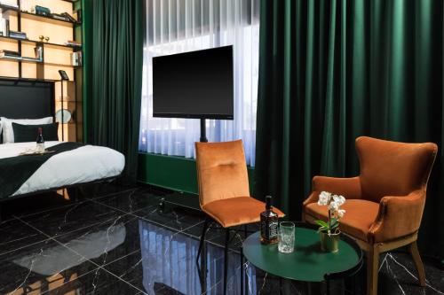 a bedroom with a bed and two chairs and a tv at Joseph Hotel TLV in Tel Aviv