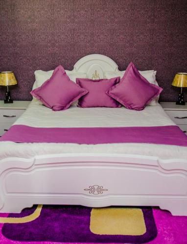 a large white bed with purple pillows on it at Aska Hotel in Naryn