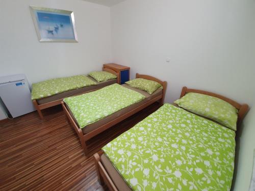 three beds in a room with green sheets at Apartments Akacijev Izvir in Miklavž na Dravskem Polju