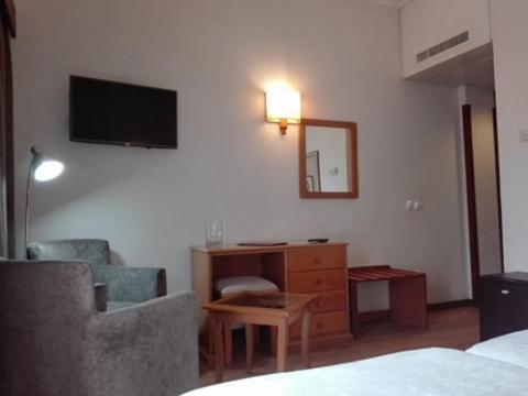 1 dormitorio con escritorio, TV y silla en Hotel Do Centro en Funchal
