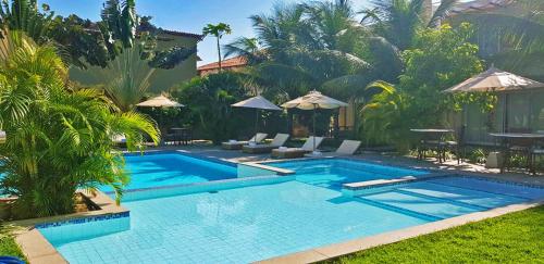 a pool with chairs and umbrellas in a yard at Ravenala Hotel Boutique in Canoa Quebrada