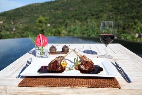 a plate of food on a table with a glass of wine at The Griya Villas and Spa in Amed