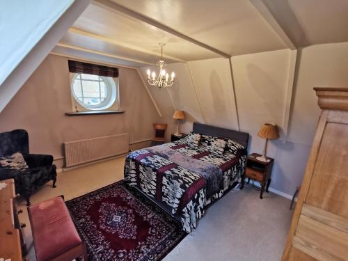 a bedroom with a bed and a chair and a window at Leithen Lodge in Innerleithen