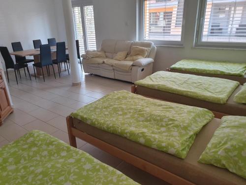 a room with four beds and a couch and a table at Apartments Akacijev Izvir in Miklavž na Dravskem Polju