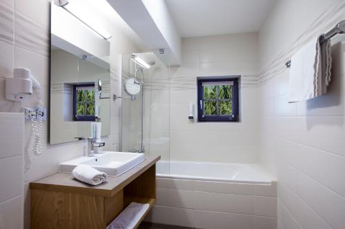 a white bathroom with a sink and a bath tub at Hotel Mariasteinerhof in Mariastein