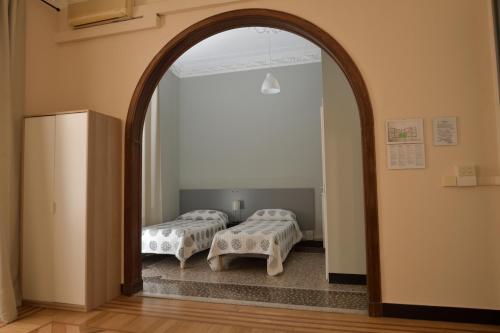 an archway leading into a room with two beds at Check-Inn Rooms Genova Centro in Genova