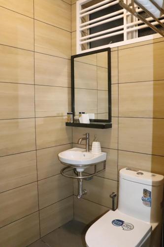 bagno con lavandino, servizi igienici e specchio di BELLE VILLE a Muar