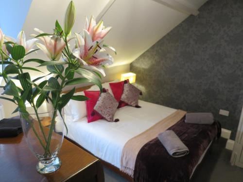 a bedroom with a bed with a vase of flowers on a table at Parkside Apartments in Newcastle upon Tyne