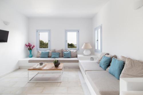 a white living room with a white couch and blue pillows at The Sand Collection Villas in Santa Maria