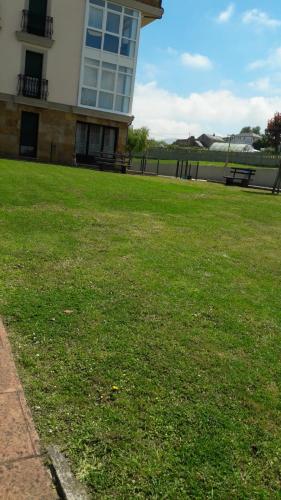a building with a field of green grass next to a building at Panoramico Playa de Altar I in Barreiros