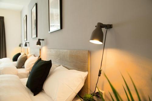 a room with a bed with white pillows and a lamp at Home In Tainan in Tainan