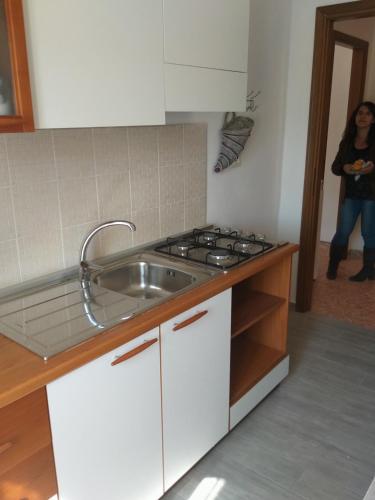 a woman standing in a kitchen with a sink at La Casa di Zoe - Terre del Magra in Bocca di Magra