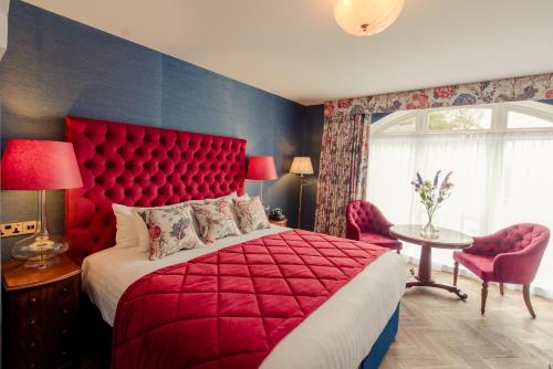 a bedroom with a red bed and a table and chairs at Cahernane House Hotel in Killarney