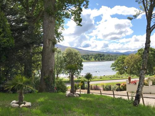 a view of a lake from a park with trees at TOM BEAG - Ben Nevis view ROOMS in Fort William