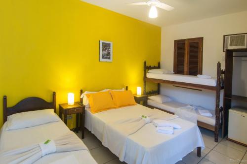 twee bedden in een kamer met gele muren bij Pousada La Cigale in Paraty