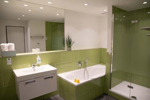 a bathroom with a tub and a sink and a shower at Hotel Le Village in Winnenden