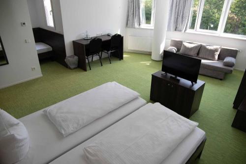 a room with two beds and a couch and a table at Hotel Le Village in Winnenden
