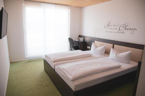 a bedroom with two beds and a large window at Hotel Le Village in Winnenden