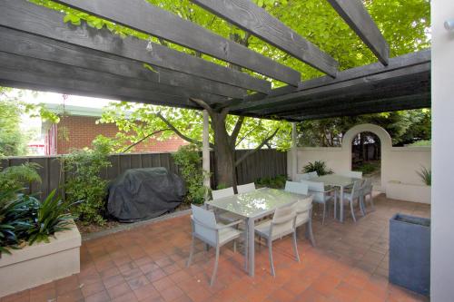 a patio with a table and chairs under a wooden pergola at Grosvenor Court Apartments in Hobart