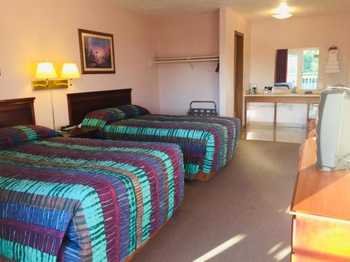 a hotel room with two beds and a television at Mountain Country Motor Inn in Branson West